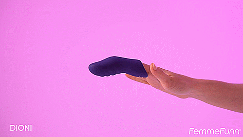 The FemmeFunn Dioni on a finger in front of a pink background. The vibrator looks like an extension of the finger, and the person twists their wrist to showcase the texture on the frontside of the vibrator. | Kinkly Shop