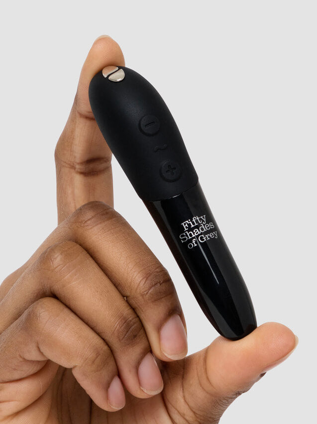 A person holds the We-Vibe Tango X that comes with the Fifty Shades of Grey Come to Bed Kit. It is a very slender vibrator, and it is barely thicker than the person's finger. It looks like it's slightly longer than the person's finger. | Kinkly Shop