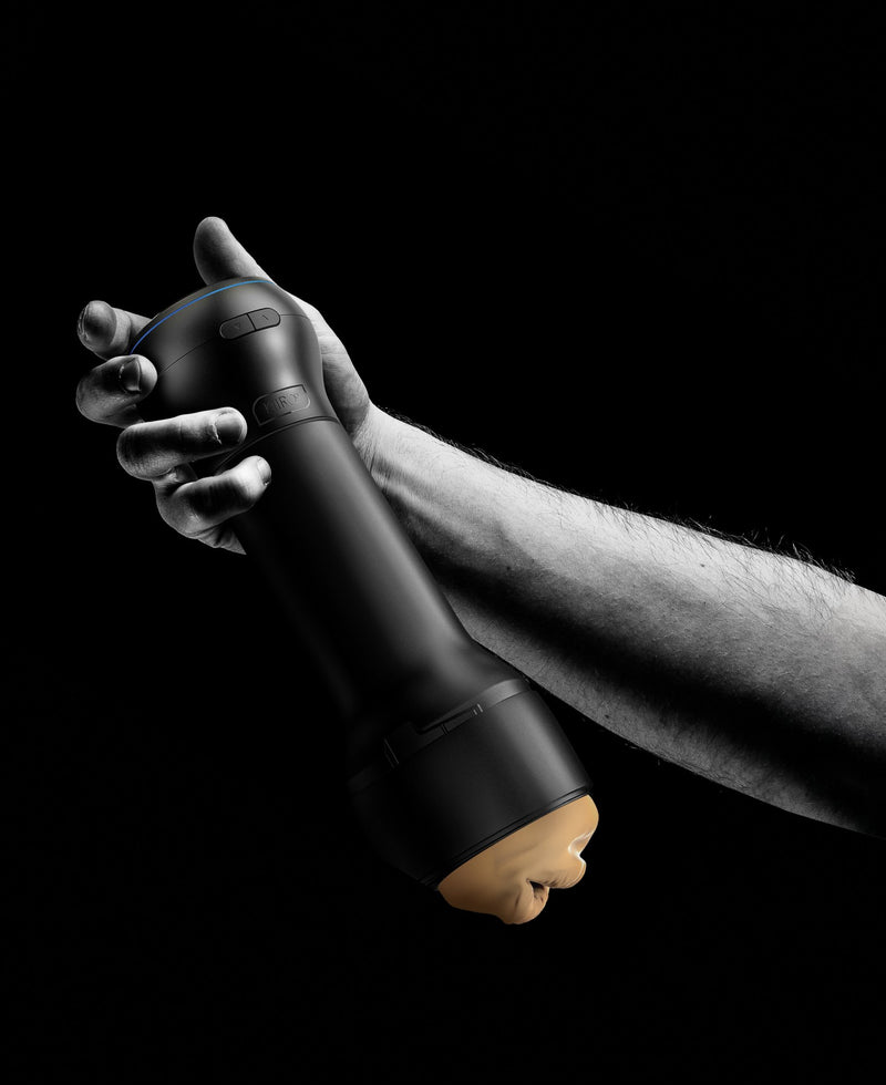 A hand holds the KIIROO PowerBlow Attachment. The Power Blow's slightly thickened diameter makes it an easy gripping point for a hand. The two buttons on the side of the KIIROO PowerBlow Attachment look like they could be operated by the person's thumb. | Kinkly Shop