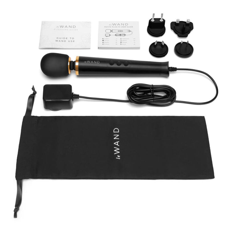 The Le Wand Petite Plug-In Massager in black with everything it comes with. There's the wand itself, the power cord, 4 international plug-in plates, a guide to using the wand, the technical manual, and a drawstring bag to store all of it. | Kinkly Shop