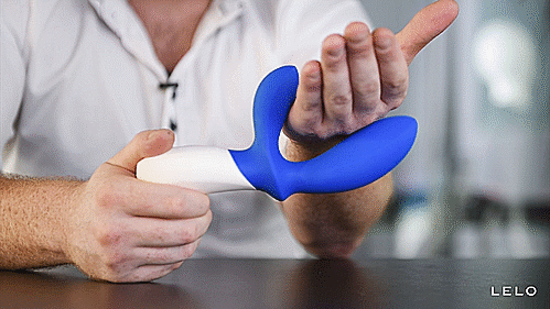 GIF showcases a person holding the LELO LOKI Wave with their other hand pressed in-between of the perineum vibrator and the come hither moving shaft. The vibrator is trying to squeeze their hand with the moving shaft. | Kinkly Shop