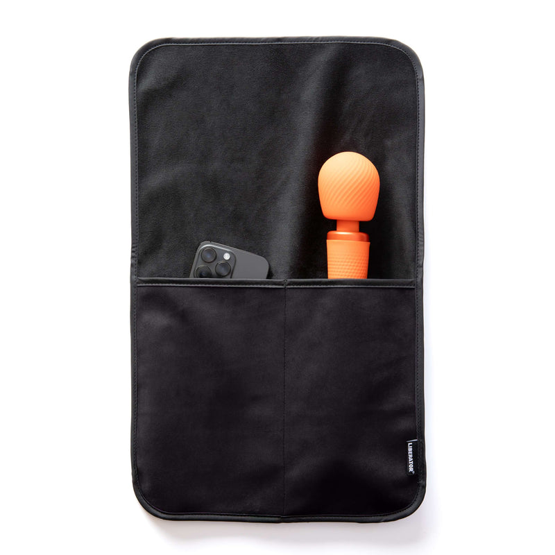 The Liberator Fascinator Sex Toy Caddy in Black laying flat on a white surface. A wand massager and a cell phone are shown peeking out from the tops of the pockets. The full length of the wand massager fits within the deep pocket, leaving only the massager's head showing from the pocket. | Kinkly Shop