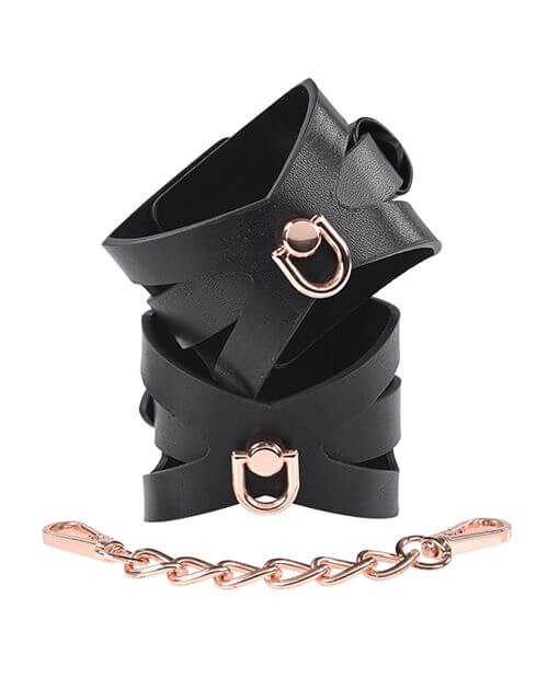 The two Sportsheets Brat Cuffs are fastened together into their cuff-like shape and stacked on top of one another. The rose gold hardware matches the rose gold hardware of the included chain. The cuffs look very unique and fashion-forward. | Kinkly Shop