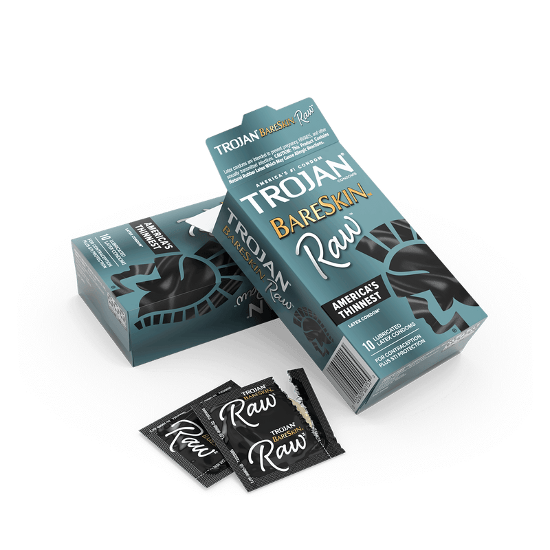 The Trojan Bareskin RAW Condoms' box opened up. A few of the individually-wrapped condoms are resting next to it, showcasing how the wrapper looks. | Kinkly Shop