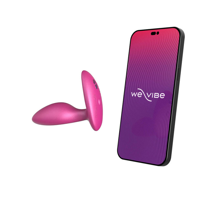 The We-Vibe Ditto+ in Cosmic Pink laid out next to a cell phone that's open to the We-Vibe Connect app. | Kinkly Shop