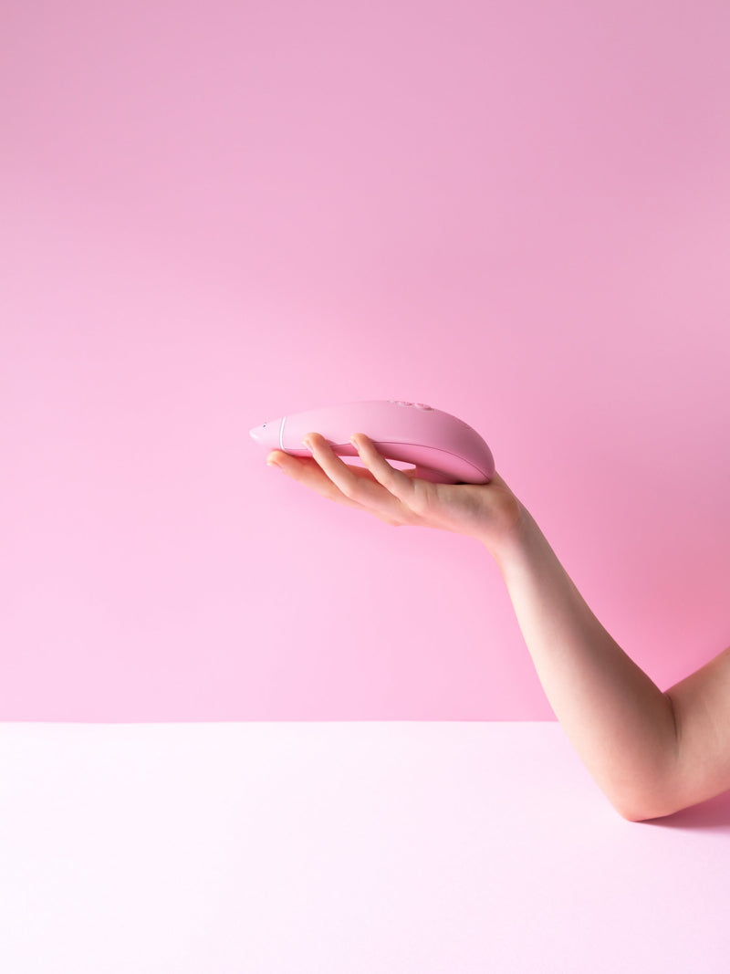 A hand holds the Womanizer Premium Eco friendly vibrator to show the relative size of the air suction vibrator to a hand | Kinkly Shop