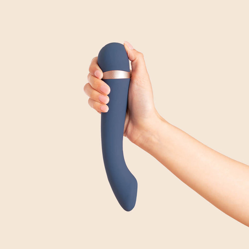 A person's hand holds the Deia Hot & Cold Temperature Play Vibrator. Their thumb is comfortably resting against the control panel while the front, flat tip of the g-spot vibrator points towards themselves. This shows a comfortable holding position for self-use of the Deia Hot & Cold Temperature Play Vibrator. | Kinkly Shop