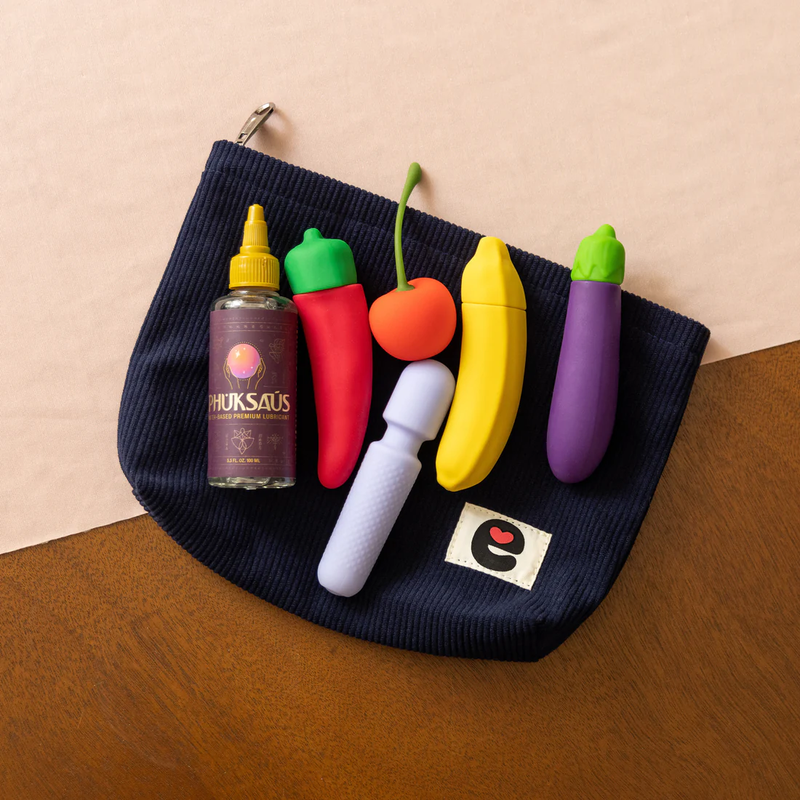 The Emojibator Pleasure Pouch sitting on a flat surface. This top-down photo shows 5 vibrators and a bottle of lube laying on top of the pouch itself, showing how all of these items would fit within its size if they were tucked inside of the pouch. | Kinkly Shop