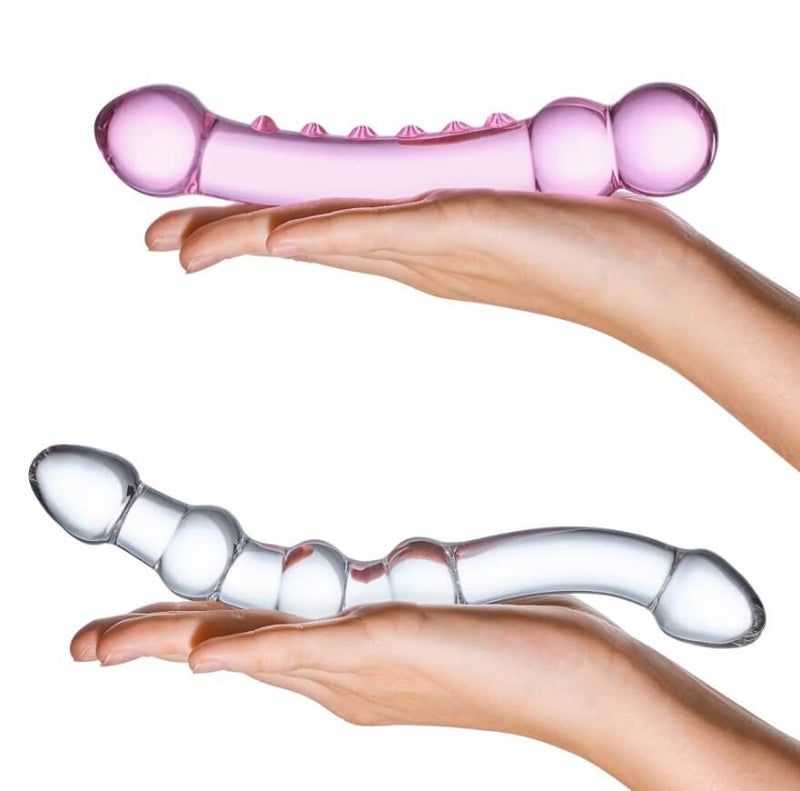 Two outstretched, flat hands hold the two dildos in the GLAS Double Pleasure Set kit. This side-by-side comparison showcases the different thickness, length, and angles of the two included dildos. | Kinkly Shop