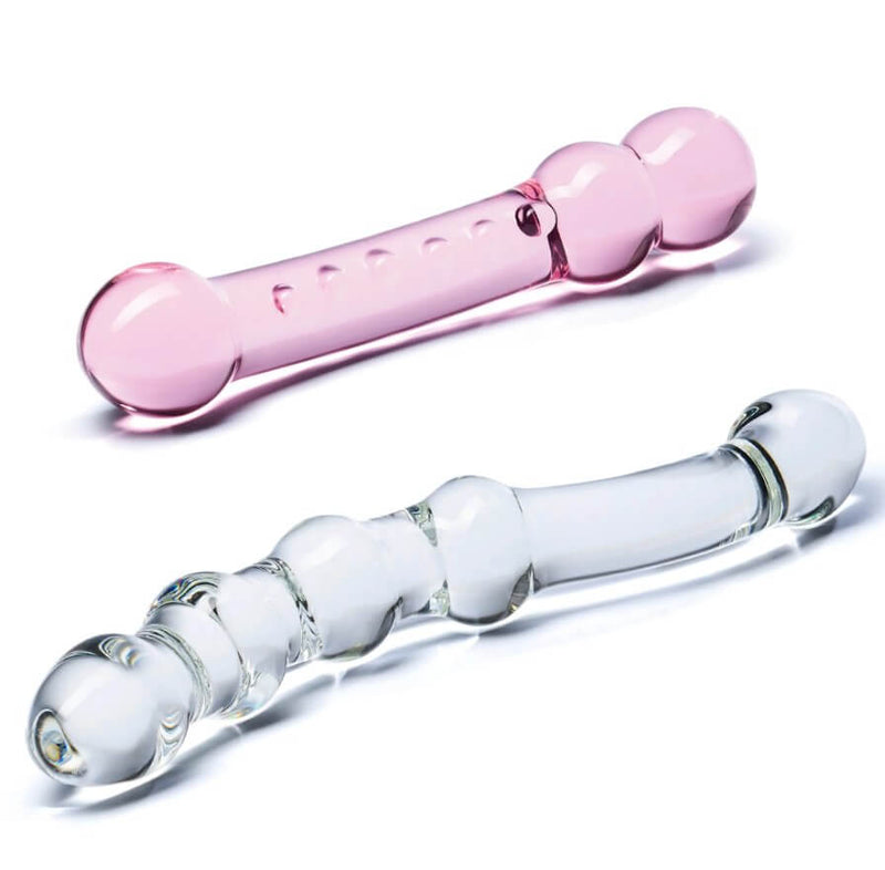 Both of the GLAS Double Pleasure Set dildos laying out. This view showcases the light pink - but still transculent - view of the pink dildo and the see-through design of the clear dildo. | Kinkly Shop
