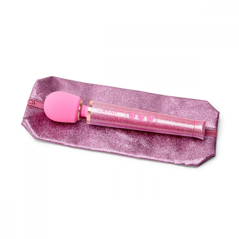 The Le Wand All that Glimmers Wand Massager laying out on top of its matching, zippered storage bag. The bag is extremely glittery and sparkly just like the wand massager is. It looks sealed with a plastic to keep the glitter from escaping. | Kinkly Shop