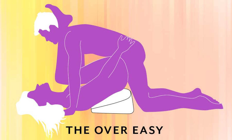 Illustrated sex position called "The Over Easy". The recipient has their hips propped up by the Heart Wedge while their thighs are pulled back towards their face. The penetrating partner is laying on top to penetrate. | Kinkly Shop