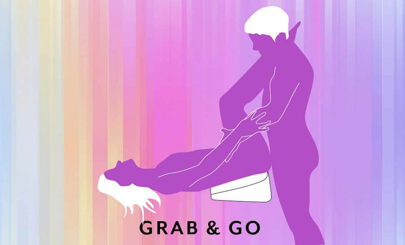 An illustrated sex position called the "Grab and Go". The receiving partner is laying on their back towards the edge of the bed with their hips elevated by the Liberator Heart Wedge. The penetrating partner is standing next to the bed and the Liberator Heart Wedge helps the receiver's hips be positioned for intercourse. Both partners are holding hands during intercourse. | Kinkly Shop