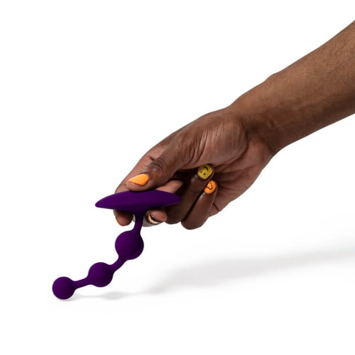 A hand holds the ROMP Amp up against a flat surface. They press the beads' tip into the flat surface showcasing as the flexible toy bends under the pressure of the movement. | Kinkly Shop