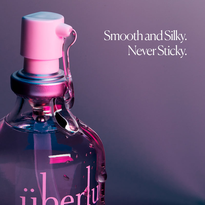 A close-up of the pump-top design of the Überlube 100ml waterproof sex lube with lube running down the spout and the bottle. Words on the image read "Smooth and Silky. Never Sticky." | Kinkly Shop