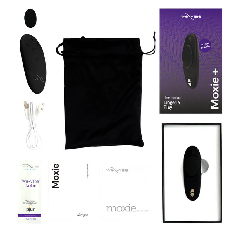 We-Vibe Moxie+ Panty Vibe in black laying out with everything that comes with the panty vibrator. This includes the panty vibrator itself, an extra backing magnet, the black physical remote control, a black drawstring bag, the magnetic charging cable, a sample-sized packet of water-based lube, an instruction manual, and safety instructions. | Kinkly Shop