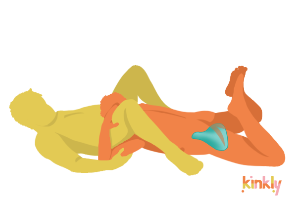 Illustrated sex position showing a giving partner laying facedown with their head providing oral sex to their partner. The Wild Flower Enby 2 is shown tucked between the giver's legs for hands-free pleasure during oral sex. | Kinkly Shop