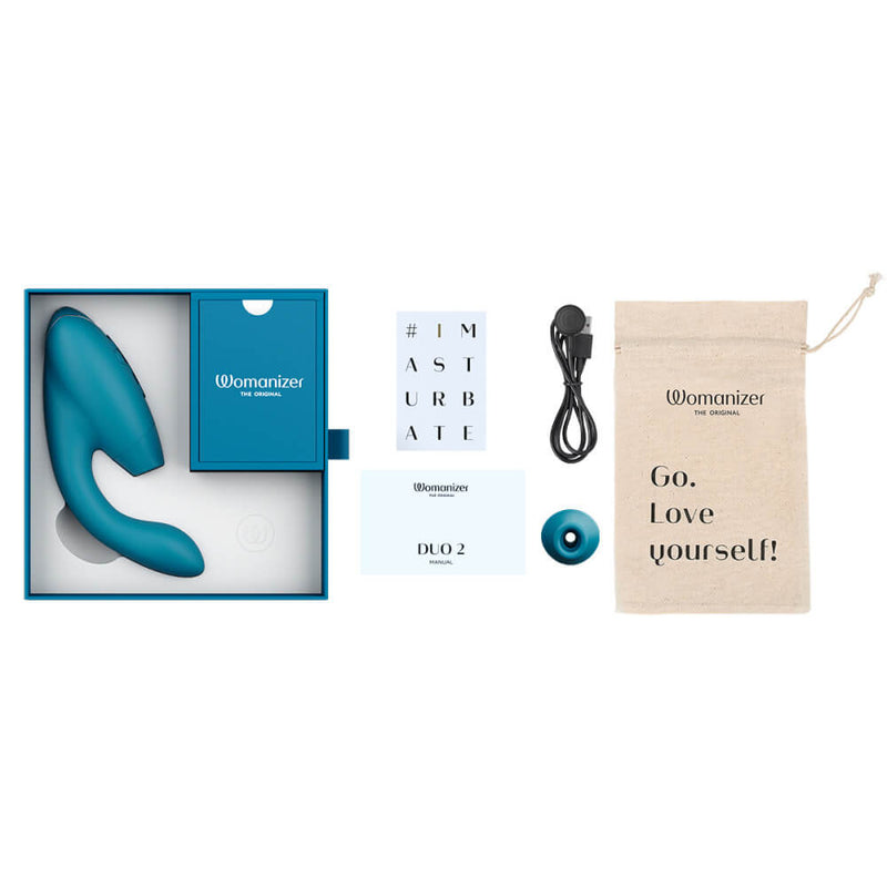 A layflat photo of the Womanizer Duo 2 shown with everything it would come with. There's the vibrator in the box, the instruction manual, the magnetic charging cable, the extra tip, and the cotton drawstring storage bag. | Kinkly Shop