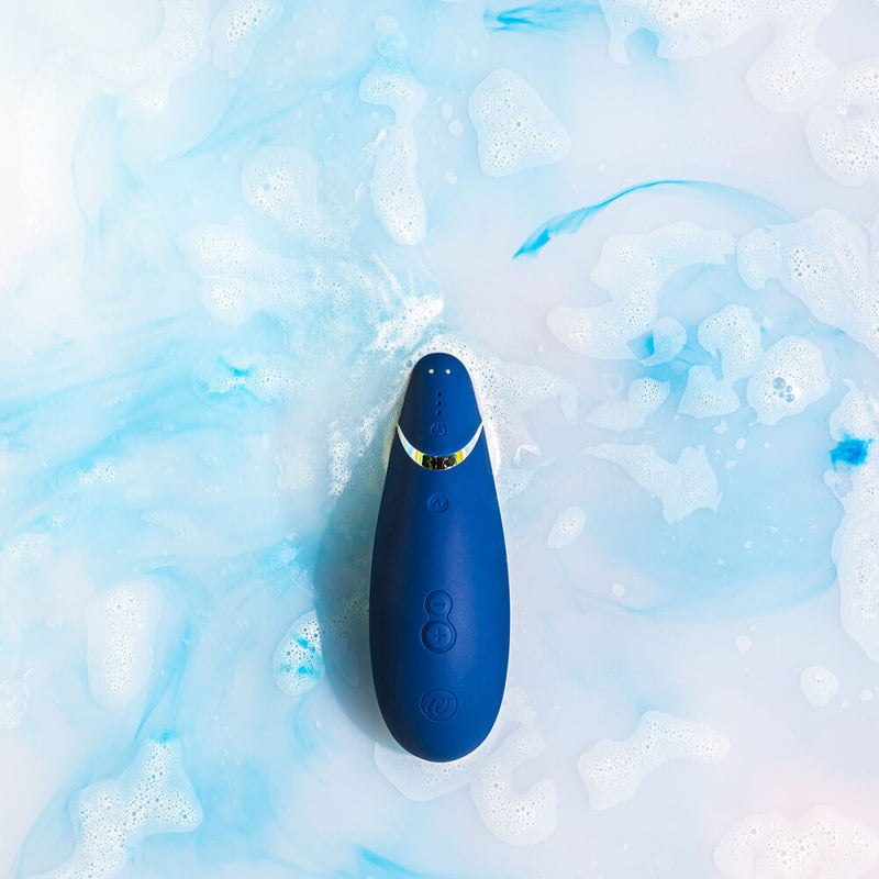 The Womanizer Premium 2 in Blueberry is sitting in a bath of blue colored water. This helps showcase the Womanizer Premium 2's waterproof capabilities. | Kinkly Shop