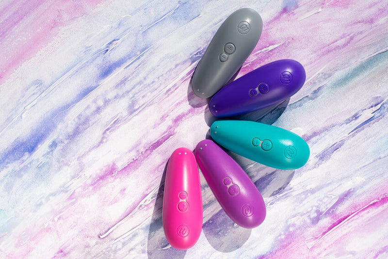 All of the five colors of the Womanizer Starlet 3 toy are sitting next to each other on top of a watercolor painting background. This allows the viewer to easily see the color differences between the different options. | Kinkly Shop