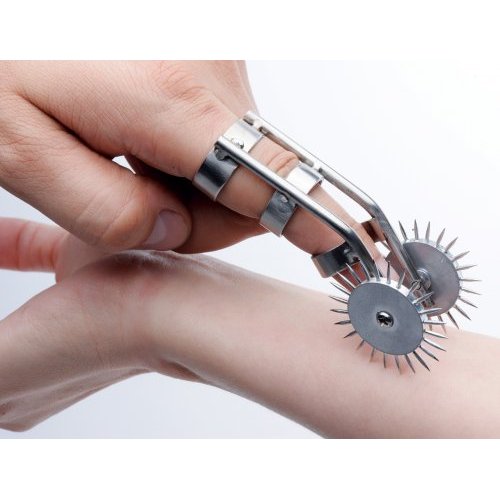A finger on a hand is wearing the XR Brands Spikes Double Finger Pinwheel. Another person is holding out their wrist and allowing the first person to use the pinwheel on their flesh. | Kinkly Shop