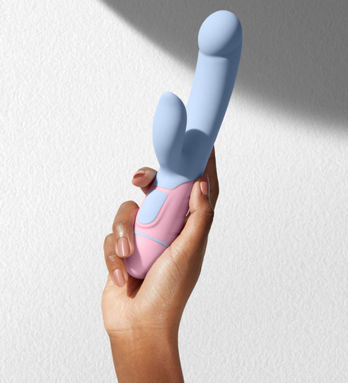 A person holds the FemmeFunn FFIX Rabbit up in front of a textured white wall. Shadows in the background make the image visually interesting. | Kinkly Shop