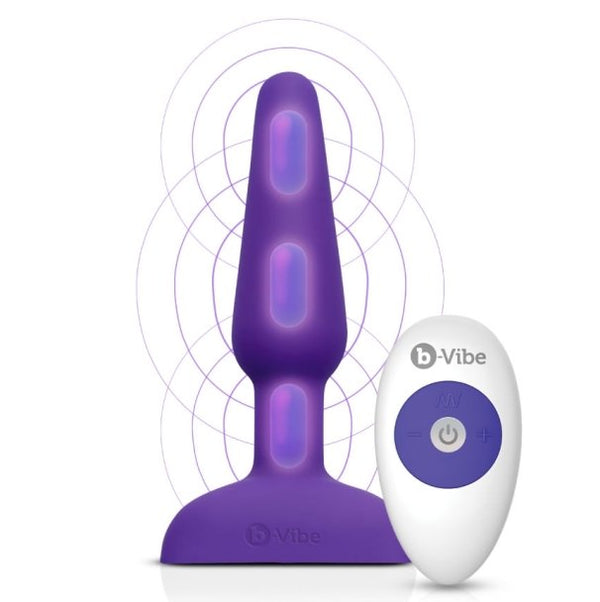 b-Vibe Remote Trio Plug in Purple against a white background. An overlayed illustration showcases where the three different motors are located on the length of the plug. One is in the tip, one is at the base of the inserted portion, and one is in the retention area of the plug. | Kinkly Shop