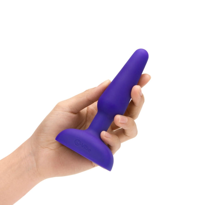 A hand holds the b-Vibe Remote Trio Plug. The plug looks very slender. It's about the length of the person's base of their palm all the way to the tip of their fingers. It looks like it's about the width of three fingers at the widest point. | Kinkly Shop