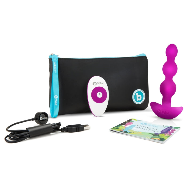 The b-Vibe Triplet Anal Beads next to everything that it includes. There's the anal beads themselves, a Guide to Anal Play, the remote control, the charging cable, and the zippered pouch to contain it all. | Kinkly Shop