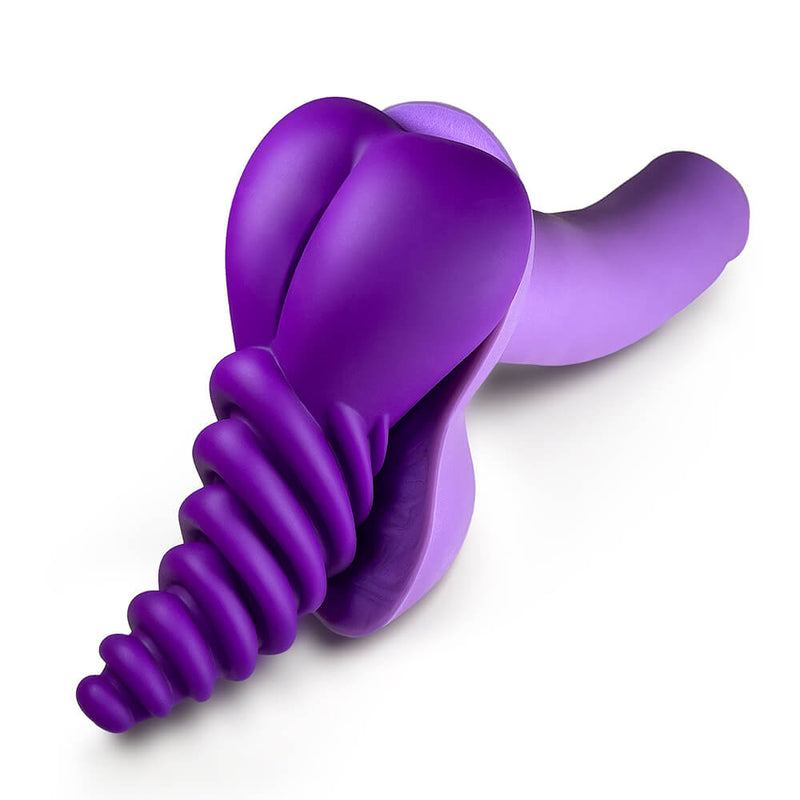 The purple LuvGrind pressed up against the base of a purple dildo that has testicles. It doesn't wrap around the base of the dildo in any way; the tacky backing of both items helps provide a non-slip surface to help hold the LuvGrind in place. | Kinkly Shop
