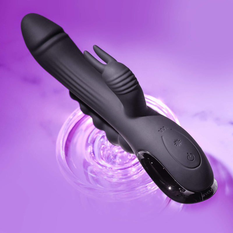Top-down view of the Evolved Trifecta in front of a purple background. This angle really showcases the texturing on the shaft and clitoral stimulator including the protruding "ears" off the clit stimulator as well. The entire toy looks futuristic. | Kinkly Shop