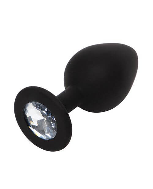 The butt plug included within the Fifty Shades of Grey Come to Bed Kit. This angle showcases the round design of the internal portion that has a tapered tip for easier insertion. The gem at the base of the plug is a white/silver gem that seems to sparkle in the photo. The retention area for the plug is very slim for comfortable wear. | Kinkly Shop