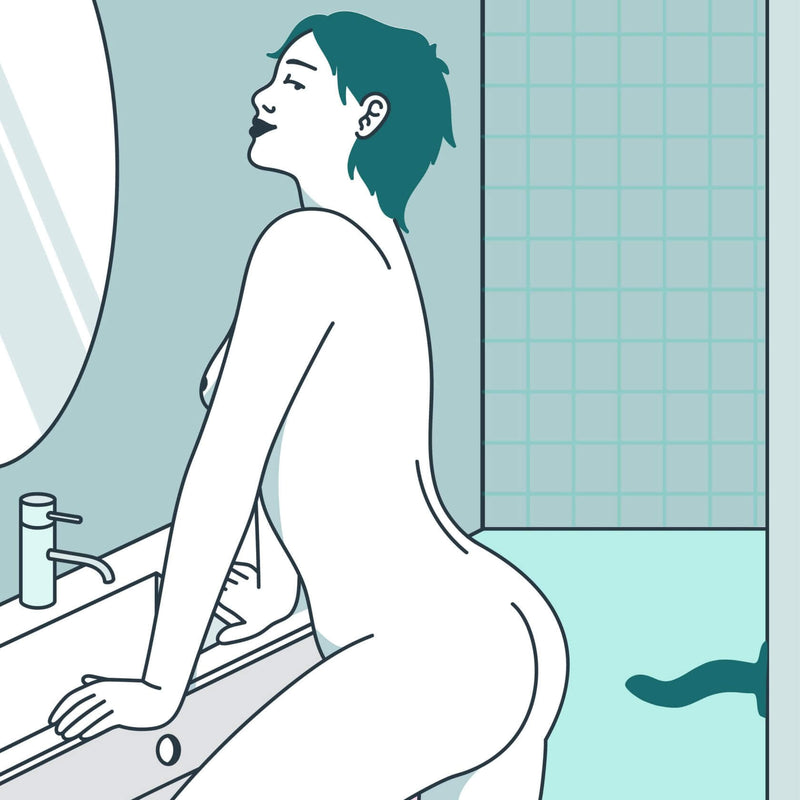 Illustration shows a naked person look at themselves in the mirror. A suction cupped Fun Factory Limba Flex dildo is protruding from the wall behind them, making it easy to back onto the dildo for hands-free play. | Kinkly Shop