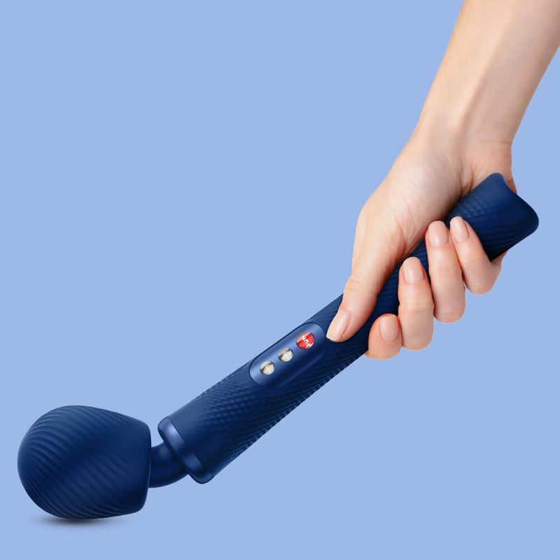 A hand holds the Fun Factory VIM, pressing it into a hard surface at the base of the image, showcasing how far the head of the wand massager will bend when pressure is applied. | Kinkly Shop