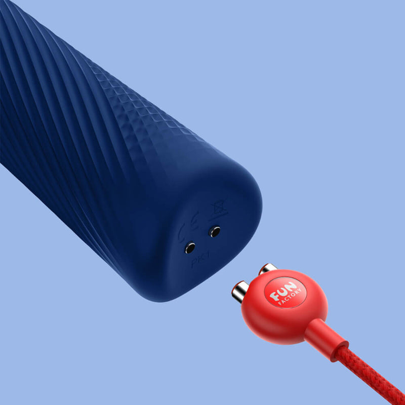 A close-up of the base of the Fun Factory VIM handle, showcasing the two magnetic prongs at the base of the toy. The magnetic charger is shown nearby, showing how the two pieces fit together to charge the vibe. | Kinkly Shop
