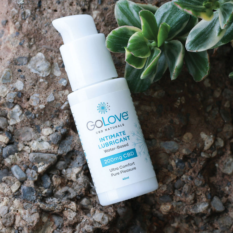 A bottle of GoLove CBD Lube - 40ml laying out on top of a rock next to a green plant. It looks natural and approachable. | Kinkly Shop