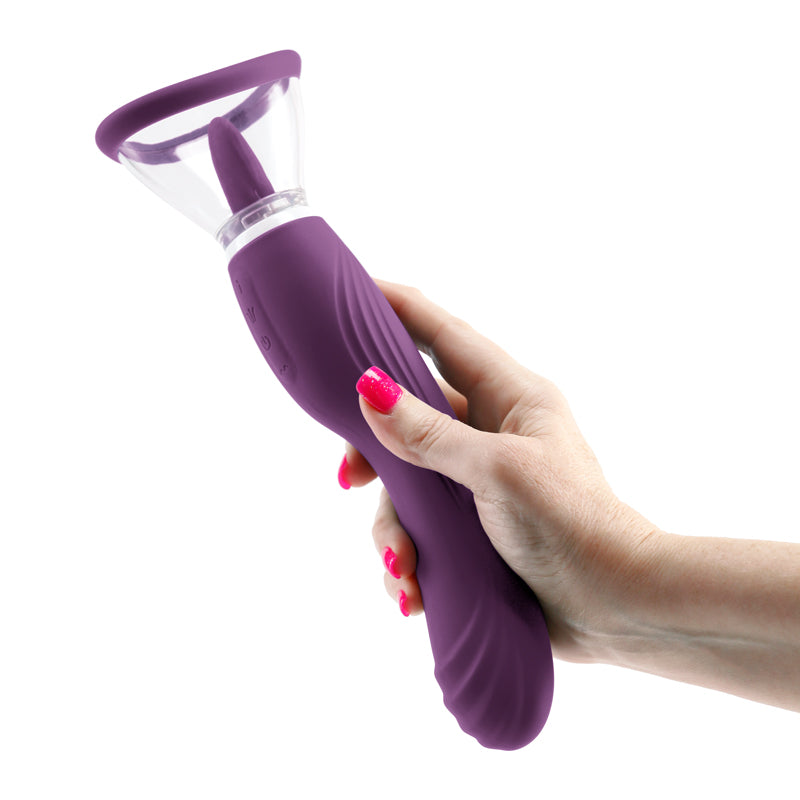 A hand holds the Inya Triple Delight. It looks like an extra-long dildo in the hand, with the fingers easily enclosed around the "shaft/handle" of the Inya Triple Delight. The licking tongue and pussy pump cap stick out at the top of the toy. | Kinkly Shop