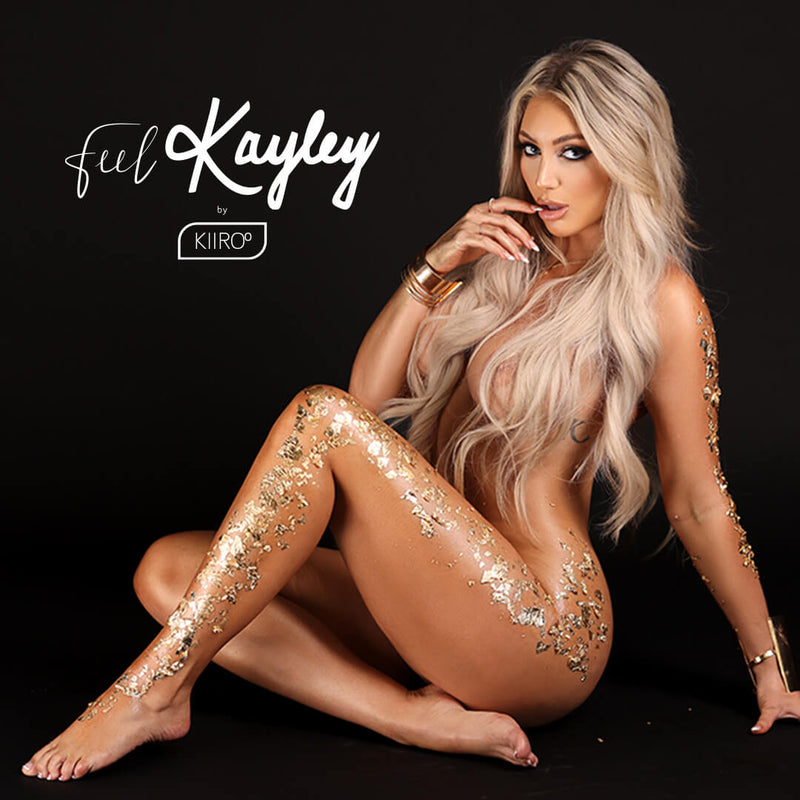 Kayley Gunner naked against a plain black background. She has a lot of gold flecking all over her body with her leg and hair strategically hiding explicit parts of her body. She looks seductively into the camera. | Kinkly Shop