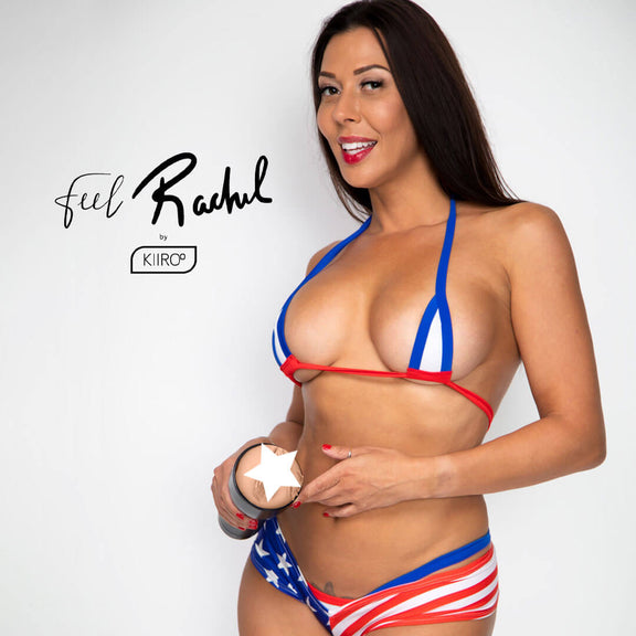 Rachel Starr smiles at the camera in front of a plain white background. She's wearing a red, white, and blue very skimpy bikini. She's holding the KIIROO FeelStars FeelRachel Stroker towards the camera. | Kinkly Shop