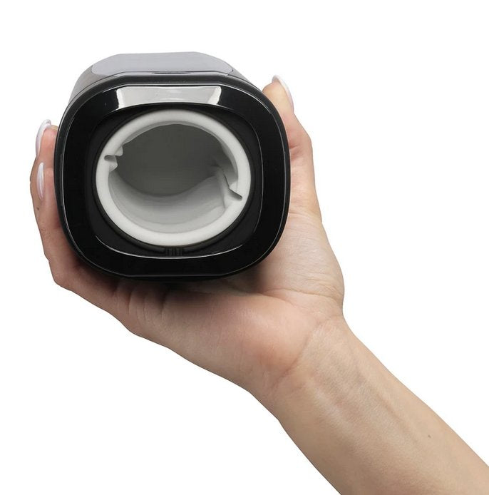 A hand holds the KIIROO Onyx+ stroker with the opening orifice facing the camera. This showcases the "open" chamber where the penis is inserted. Slight ribbing can be seen where the rings of the Onyx+ are underneath the sleeve. | Kinkly Shop