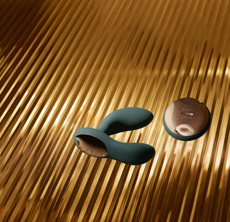 The LELO HUGO 2 in Green with Remote laying on top of a textured, lined golden surface. | Kinkly Shop
