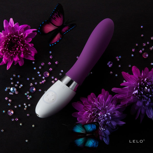 LELO LIV 2 in Plum up against a plain black background. Purple flowers and butterflies accent the vibrator, scattered around its length. The vibrator is a deep, gem-toned purple. | Kinkly Shop
