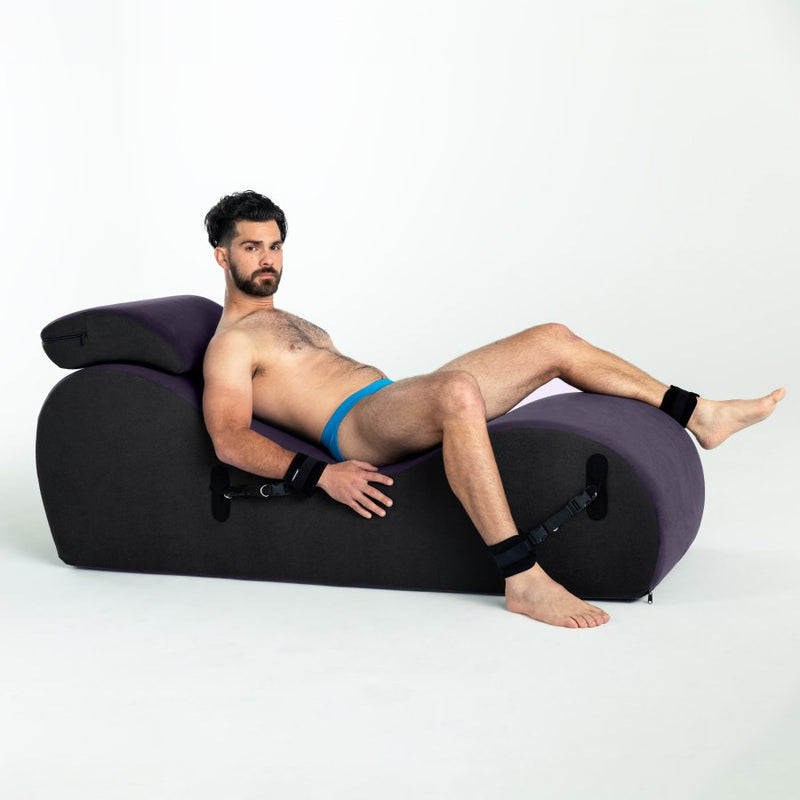 A person lounges on top of the Liberator Black Label Lyza Lounger Valkyrie. Their wrists and ankles are restrained to the sex furniture underneath them. They look extremely comfortable and supported. | Kinkly Shop