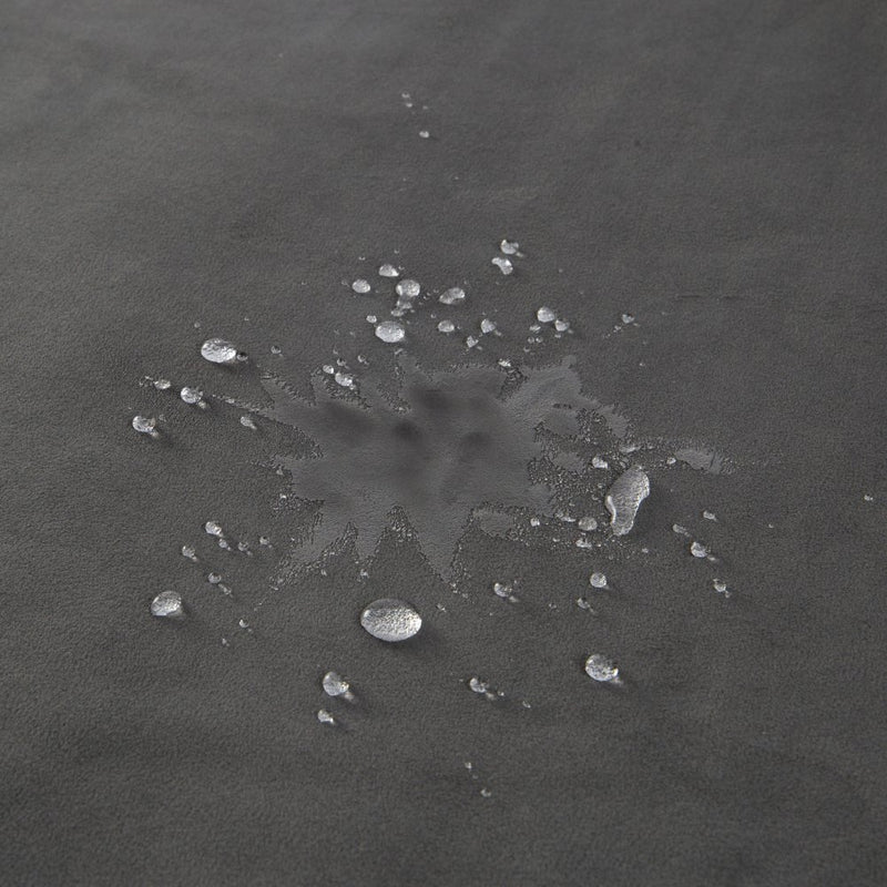 Water is poured onto the surface of the grey Liberator Fascinator Throw. Some of the water has absorbed into the blanket, but some of the water droplets still look like droplets on top of the surface of the blanket, not absorbing into the material. | Kinkly Shop