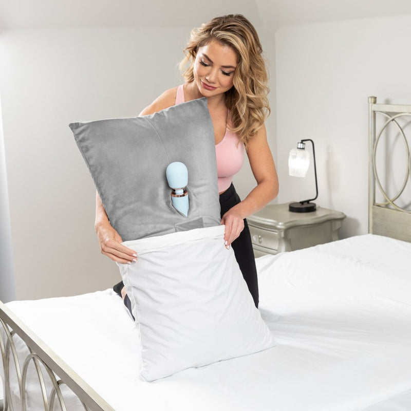 A person in workout clothing is putting the Liberator Humphrey with a wand massager inside of it into a white pillowcase. The Humphrey is long, about the person's entire height when they're kneeling on the bed. The end of the Liberator Humphrey that's in the pillowcase looks like a standard pillow inside the pillowcase. | Kinkly Shop