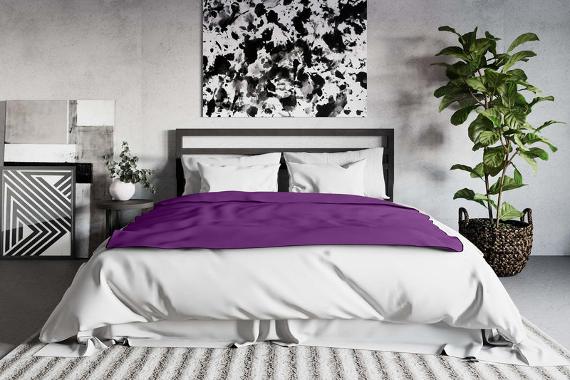 The Liberator Fascinator Throw in Regular, Purple, Aubergine color and size laying on top of a bed. It covers most of the bed, and it looks welcome and soft. | Kinkly Shop