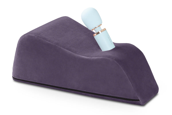 The Liberator Wanda in Plum Purple up against a plain white background. There's a blue wand massager sitting in the Wanda is protruding upwards at an angle. | Kinkly Shop