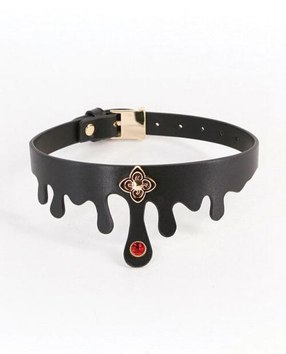 The NS Novelties Elvira Collar in front of a plain white background. It's made of a black faux leather with blood "droplets" built into the collar's shape. There's a gold charm and a gem on the center front of the collar. It has a color-matching gold buckle on the backside of the collar to adjust the circumference. | Kinkly Shop