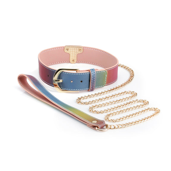 The NS Novelties Spectra Rainbow Collar and Leash up against a white background. The interior faux leather color is a light pink while the external color is a rainbow ombre. All of the hardware is a shiny gold. | Kinkly Shop