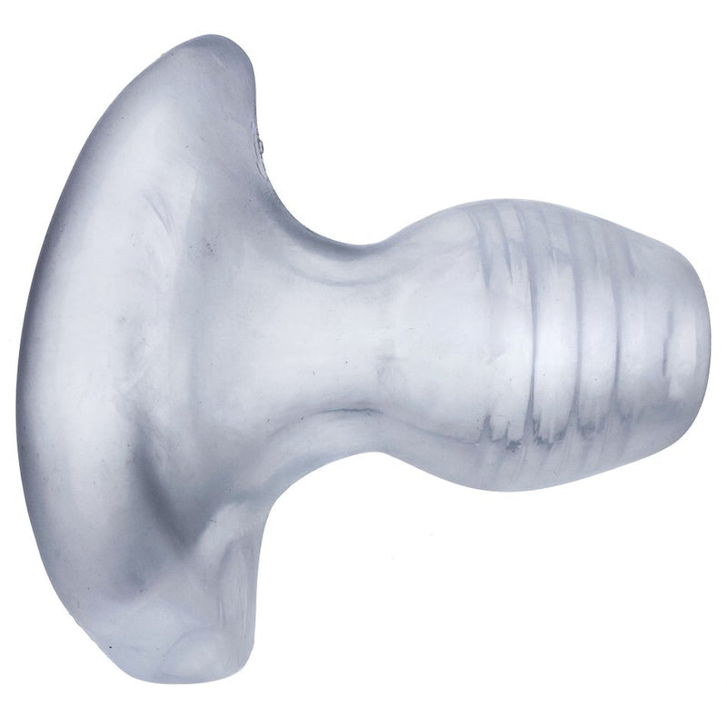 A side view of the see-through material of the Oxballs Glowhole. This side view showcases the wide, anchored base that sits outside of the body as well as the ribbed internal channel that would pleasure anyone penetrating inside of the anal plug. | Kinkly Shop